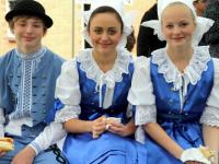 Youngsters in folklore costumes eating hot dogs